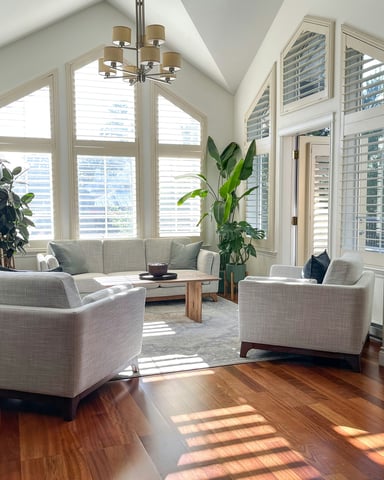 Bright vaulted living room with plantation shutters and warm wood floors