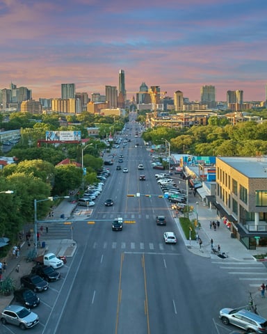 Aerial view of South Congress Avenue stretching toward the Austin skyline at sunset