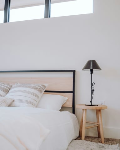 Clean modern bedroom with wood-framed bed, striped linen pillows, and clerestory windows