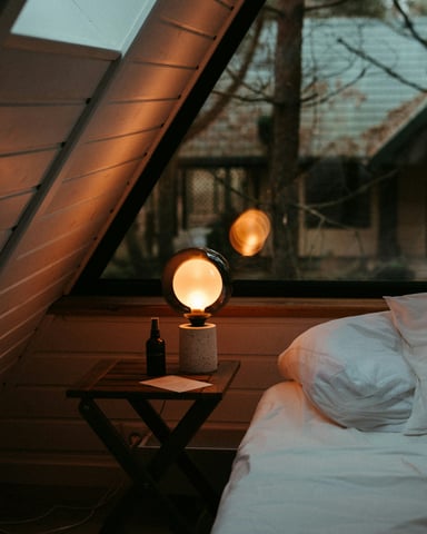 A-frame bedroom with warm glowing lamp and white pillows