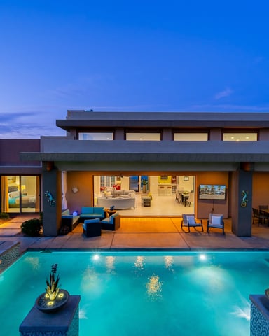 Modern home at dusk with glowing pool, spa, and outdoor lounge
