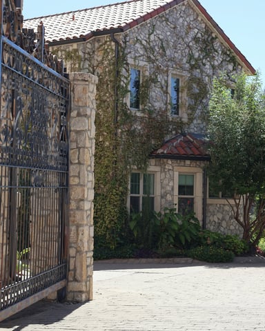 Ivy-covered limestone estate with wrought iron gates in Dripping Springs Texas