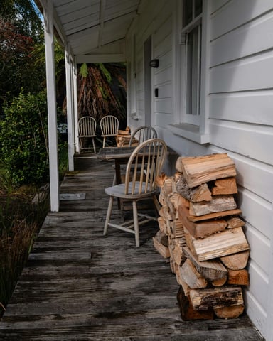 Cabin porch with stacked firewood and chairs, ready for a cool evening