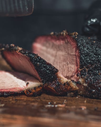Sliced smoked brisket on a wooden board with a perfect pink smoke ring