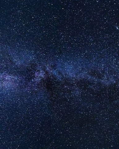 Night sky filled with stars and Milky Way galaxy stretching across dark blue expanse