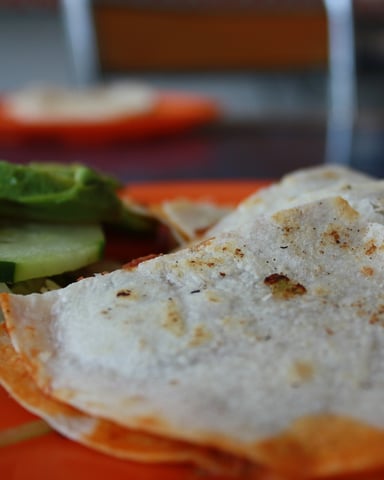 Sliced white fish fillet with black pepper on orange plate, garnished with cucumber and cabbage
