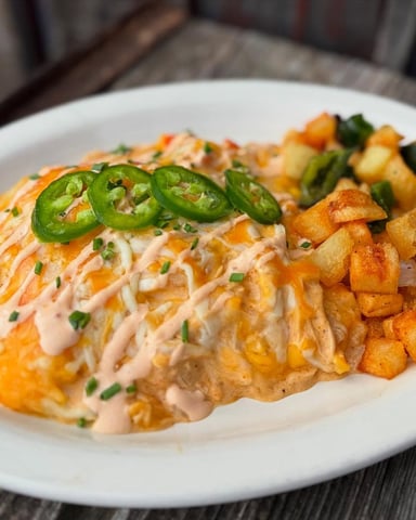 Plated salmon fillet with creamy sauce, jalapeño slices, roasted potatoes, and chives on white plate