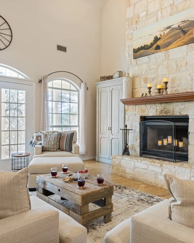 Limestone fireplace living room with vaulted ceilings, French doors, and flat-screen TV
