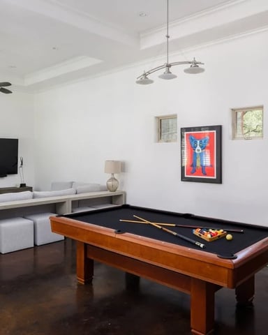 Bright game room with pool table, Atari arcade machine, and stone fireplace wall